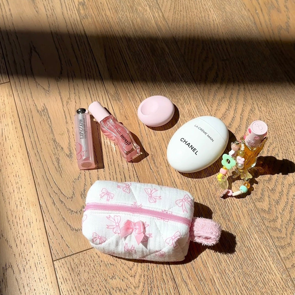 White mini pouch with pink bow print, pink zipper, fuzzy charm detail