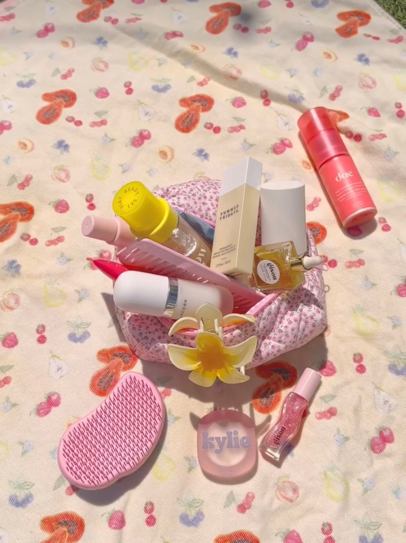 Pink ditsy floral zip pouch partially open, containing assorted beauty bottles.