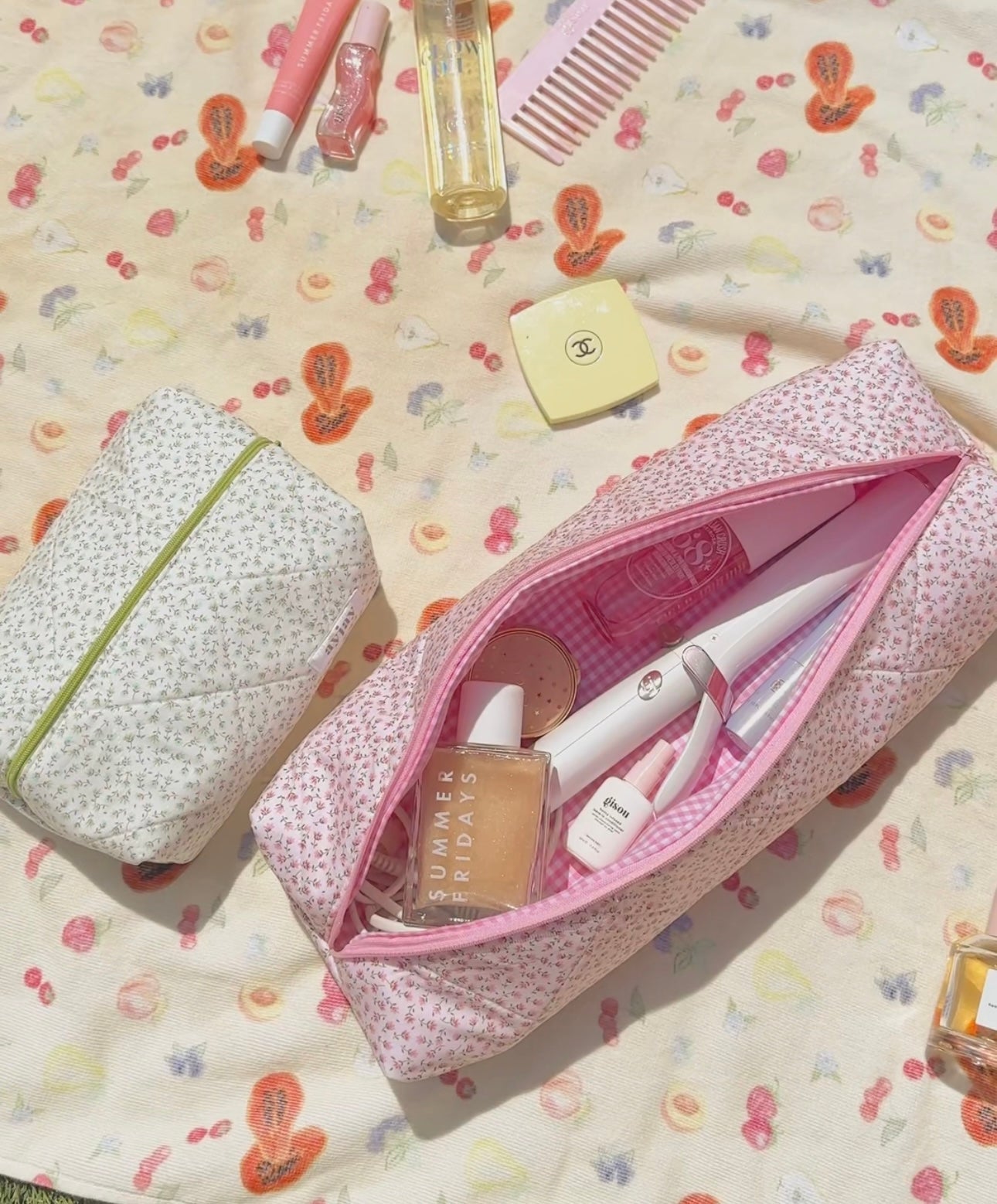 Pink ditsy floral zip pouch with pink lining, open with beauty items inside.