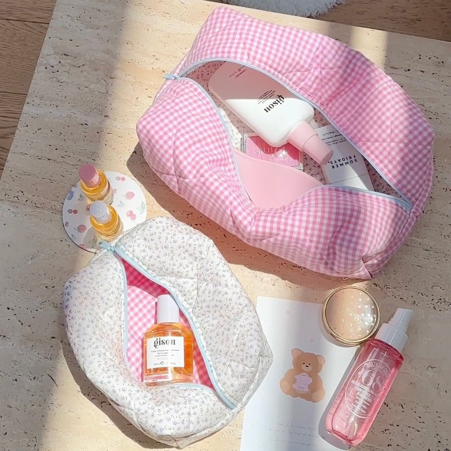 Pink gingham zip pouch open with blue zipper trim, showing inside toiletries