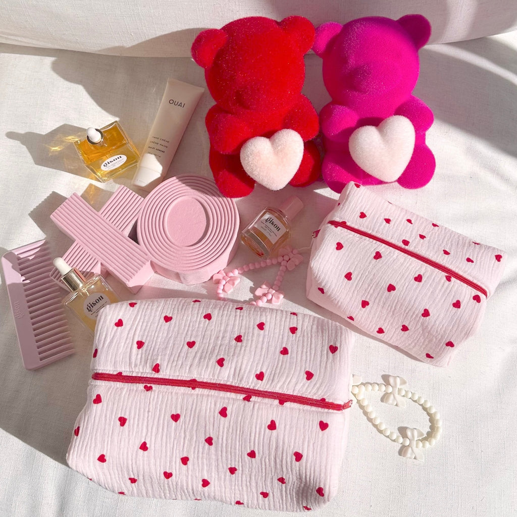 Multiple white heart-print zip pouches with red trim and red zipper openings