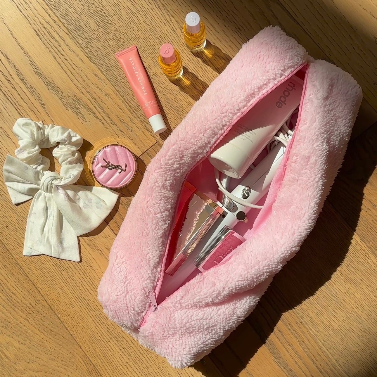 Pink soft teddy zip pouch, open at an angle with bottles and tools inside