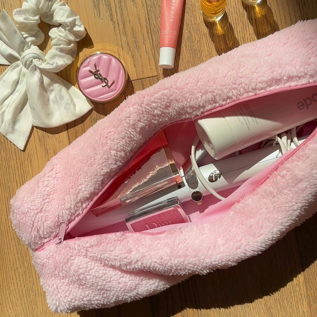 Light pink soft teddy zip pouch, open showing tubes and a spray bottle inside