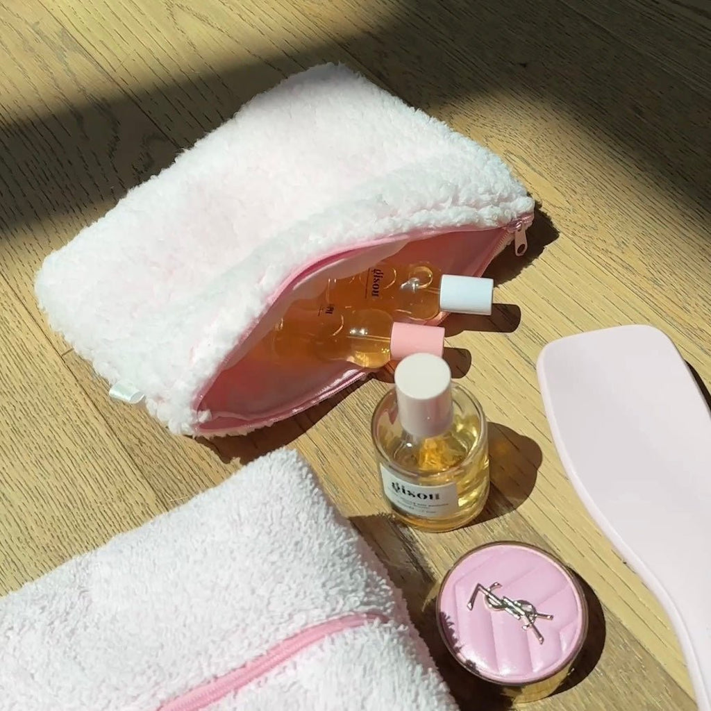 Light pink soft teddy zip pouch, open showing toiletry bottles inside