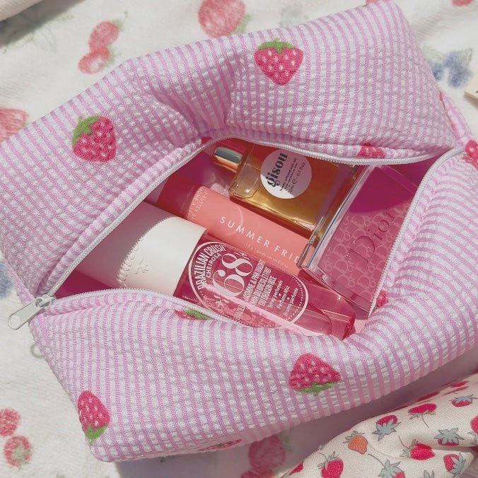 Pink striped zip pouch with heart-strawberry pattern, open with visible items inside