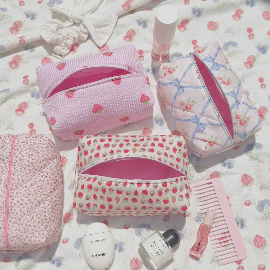 Pink striped zip cosmetic pouch with strawberry heart pattern, partially open