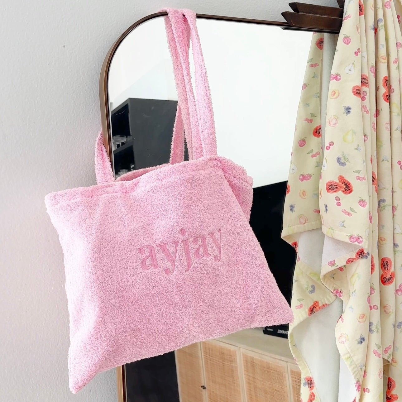 Pink terrycloth tote bag with “love” logo on front panel and tall carrying handles.