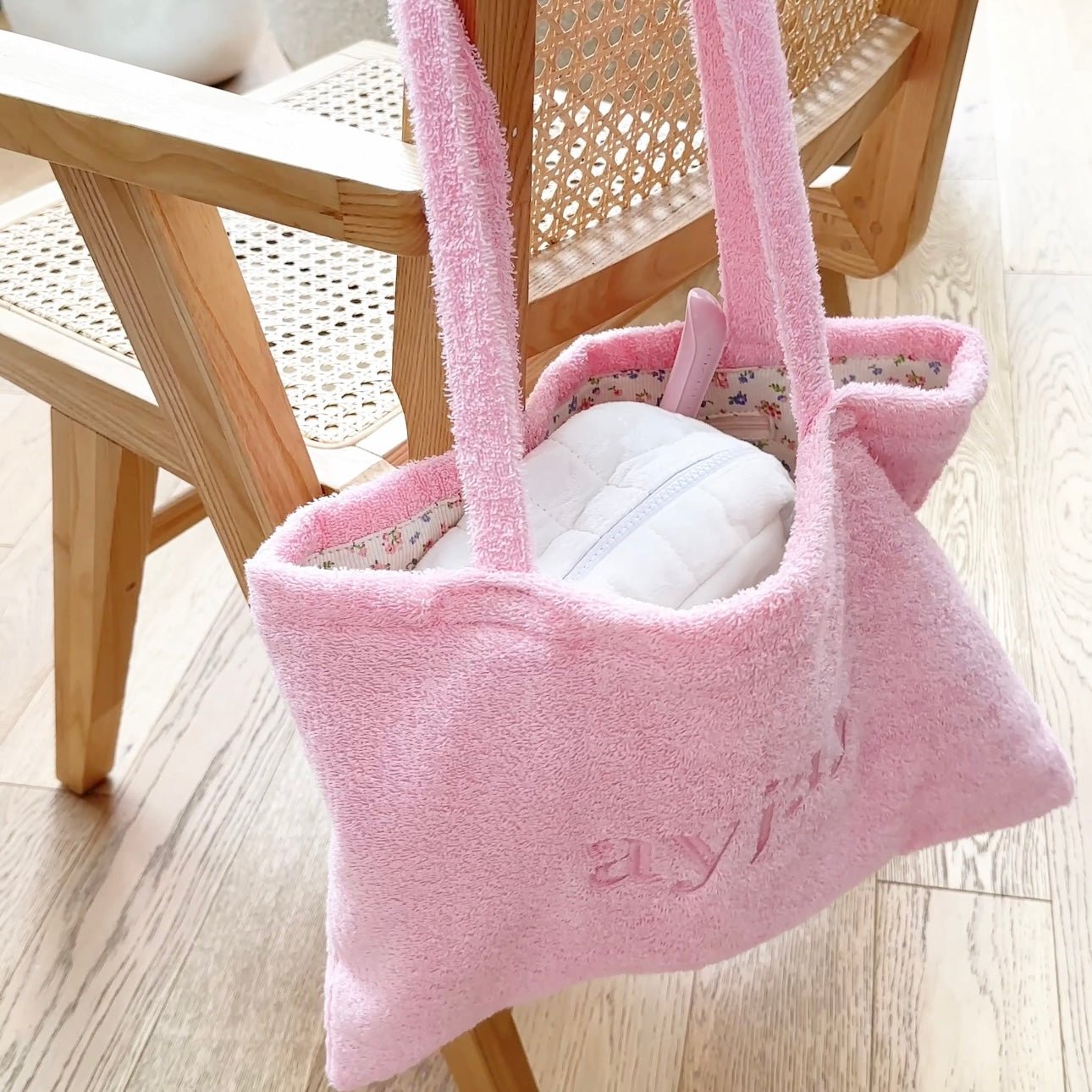 Pink terrycloth tote bag with long handles and embossed “love” text on front.
