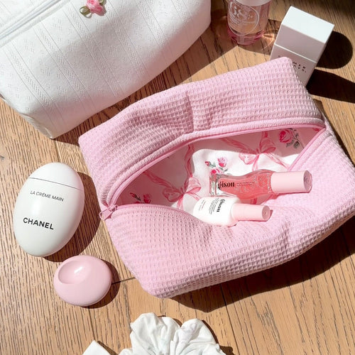 Pink waffle-knit zip pouch, bow trim, open top showing pink floral lining