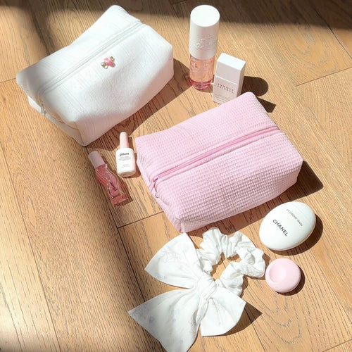 Pink waffle-knit zip pouch with bow detail, textured surface and slim handle