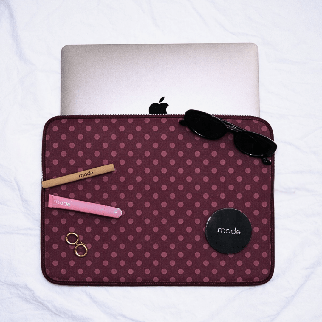 Plum polka-dot neoprene sleeve, open with zip closure; black accents.