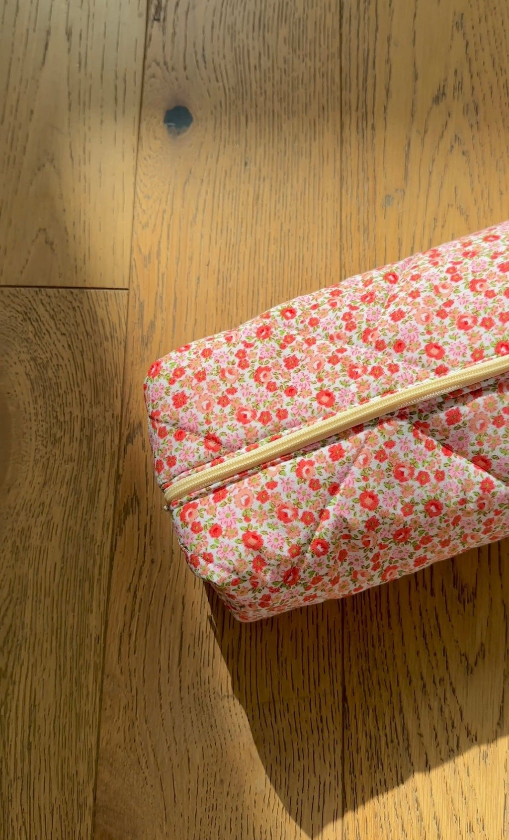 Floral zip pouch closed, close-up of zipper and top edge on wood floor