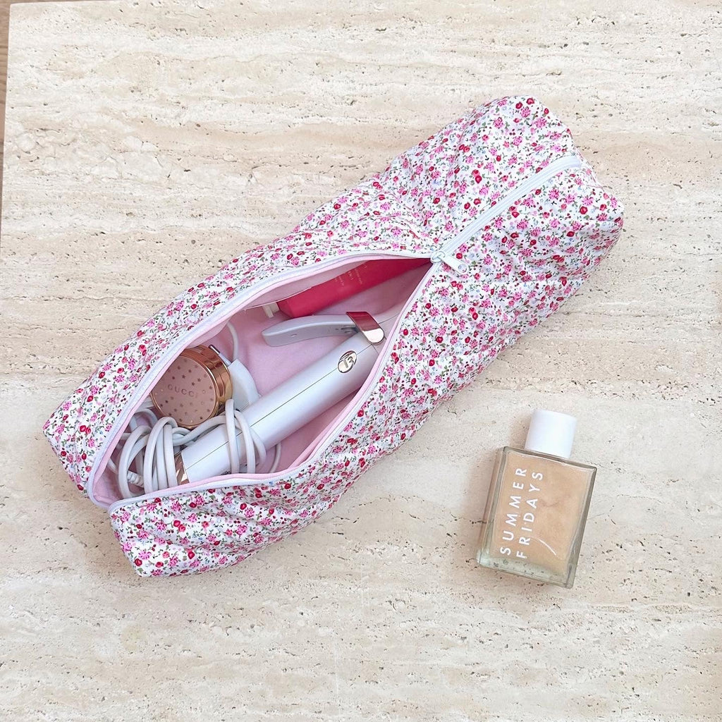 Floral toiletry bag with open zipper, pink interior and assorted toiletries visible inside.