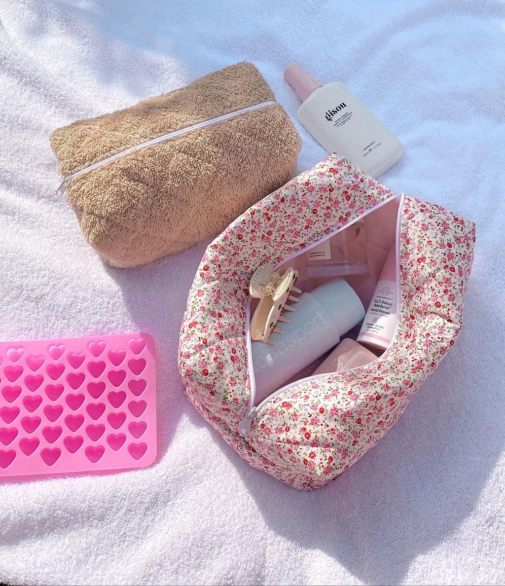 Floral toiletry bag with pink interior lining, zipper top open on light fabric.