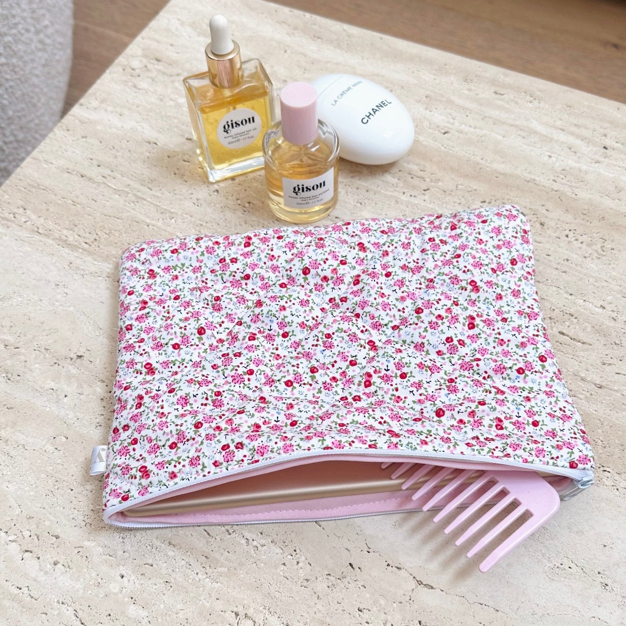 Red minimalist floral zip pouch, open top showing pink accessory and skincare bottles