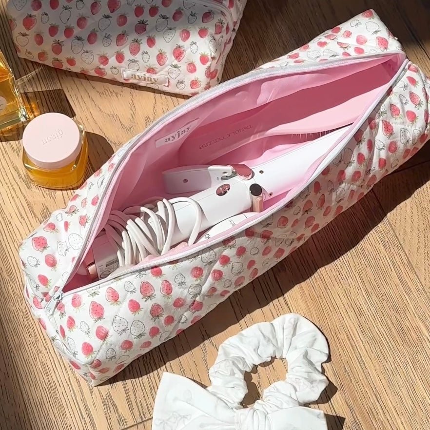 Open strawberry pouch with white hair tool and cords, pink lining