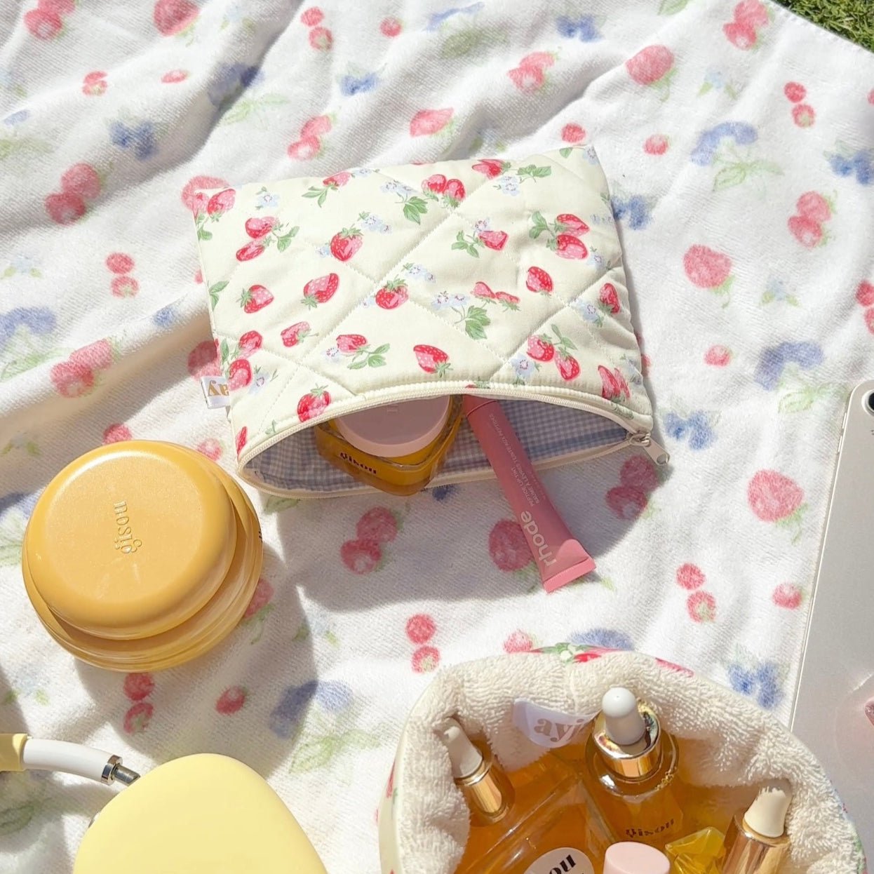Cream flat pouch with strawberry floral print, zipper top open.