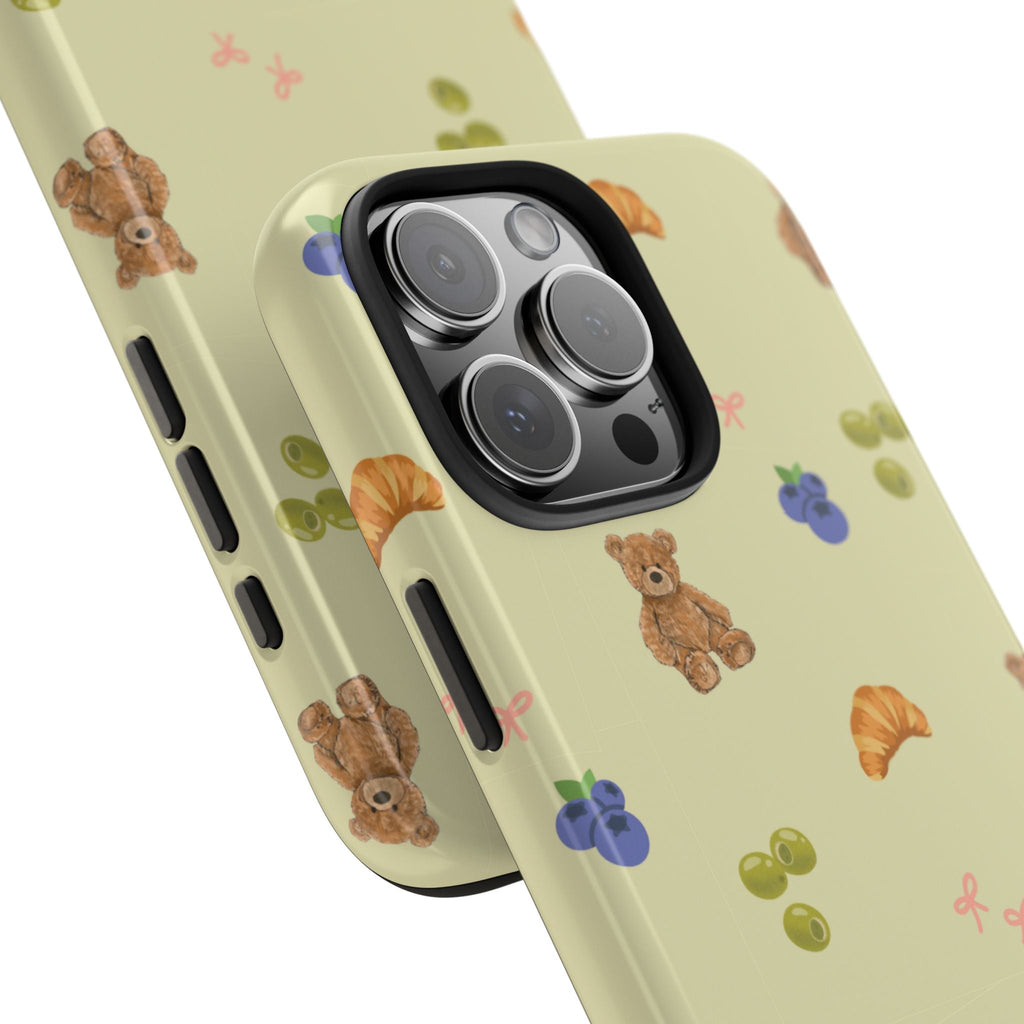 Close-up olive phone case with teddy and croissant print; raised camera cutout