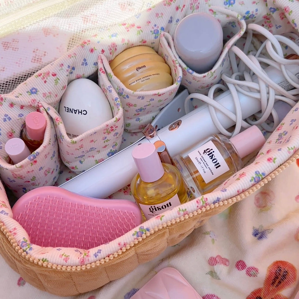 Open tan floral vanity hair tool bag with bottles, brushes, and cord organizers.