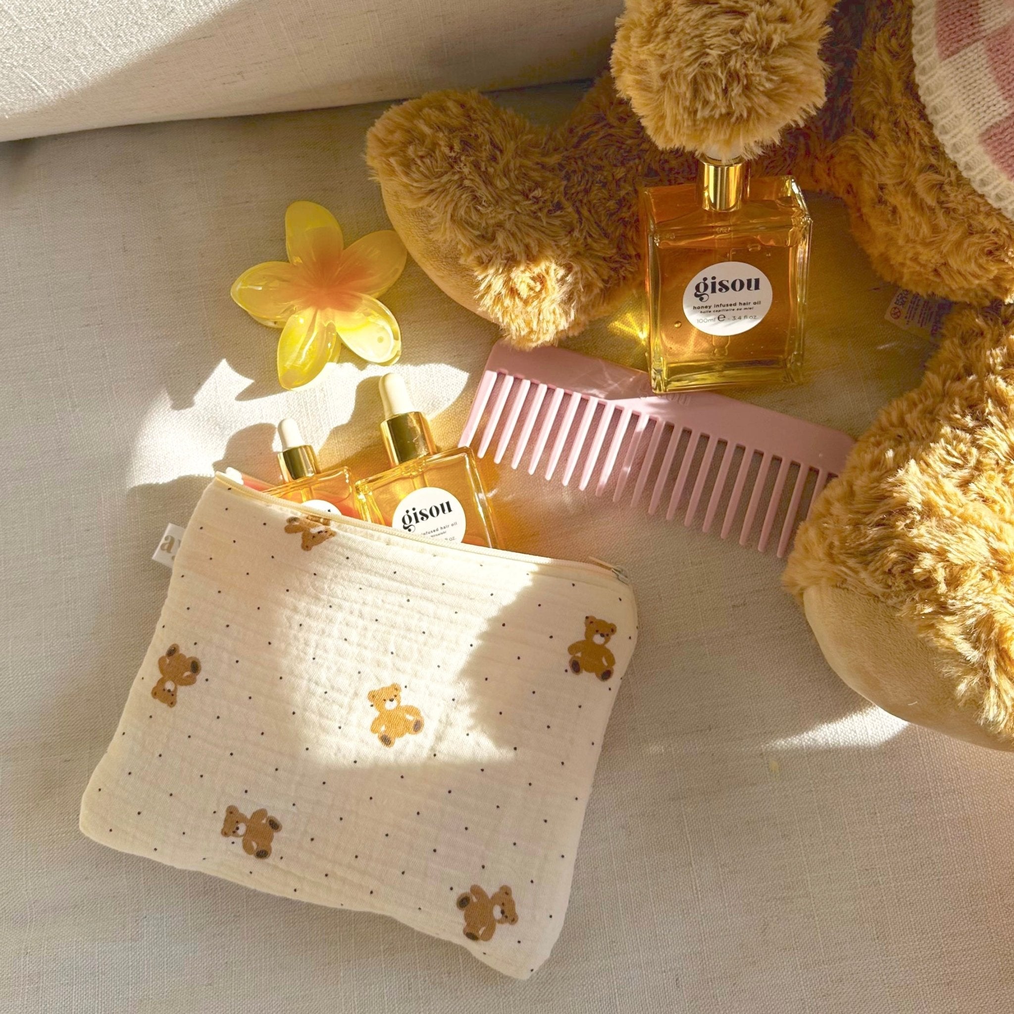 Cream teddy bear dotted pouch with zipper, rectangular shape on surface