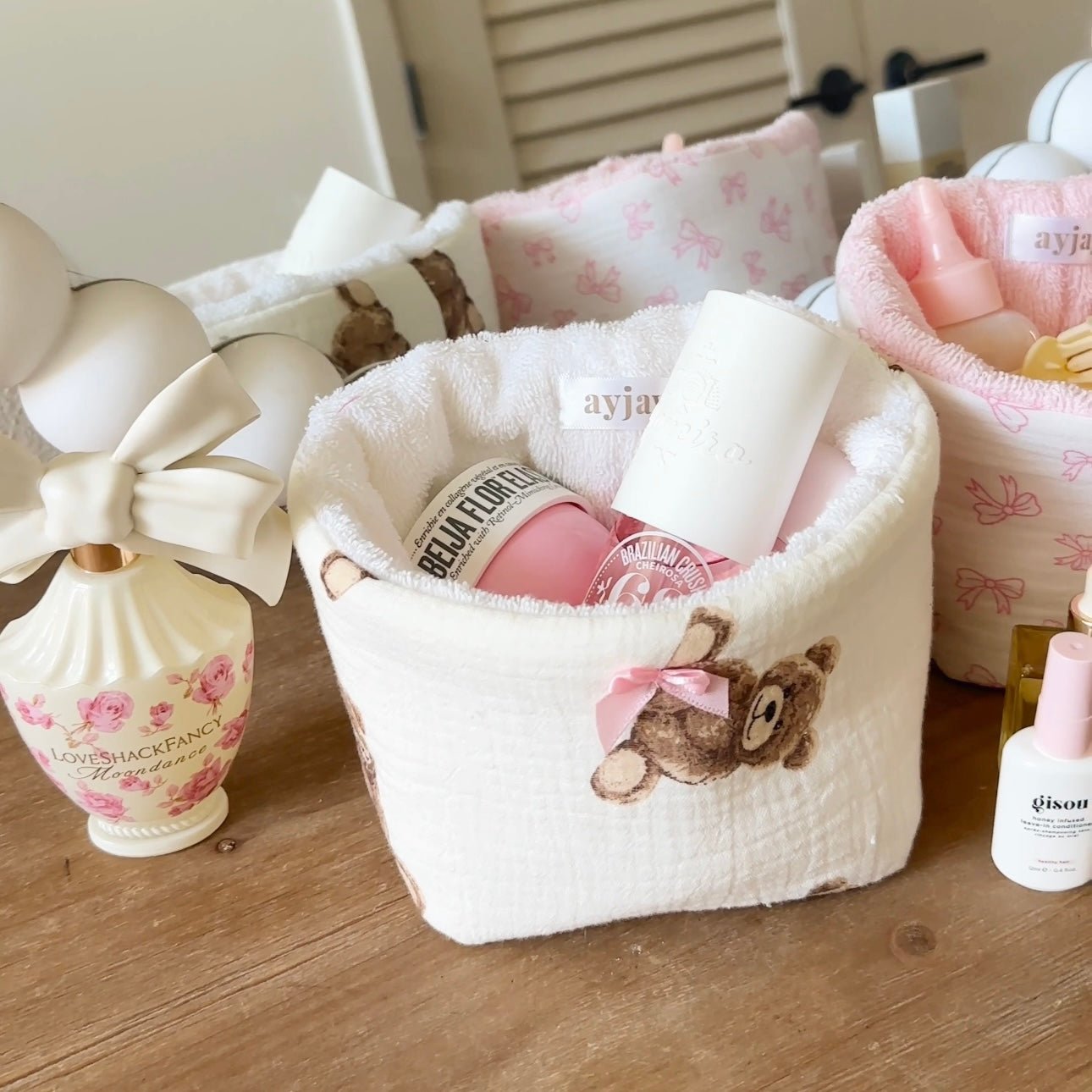 White plush teddy bear organizer with bow trim and open top, holding bottles.