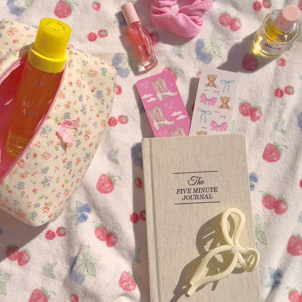 Cream “Five Minute Journal” cover with a pink ribbon bookmark card peeking out.