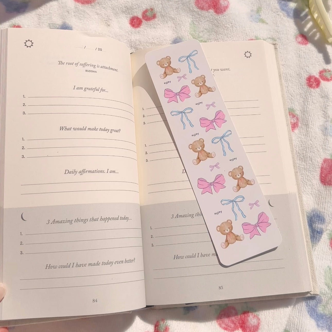 Paper bookmark with teddy bears, pink bows, and blue ribbon bows on a light background.