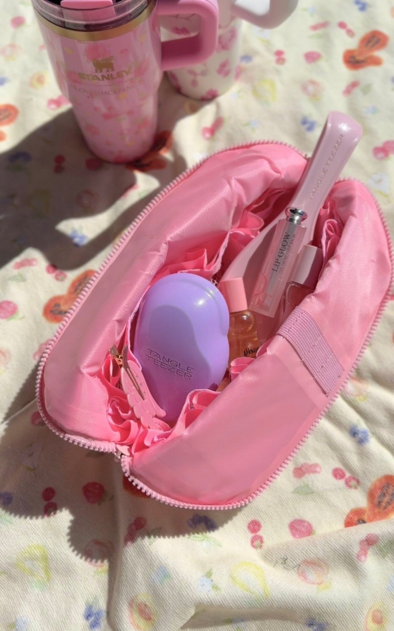 Open pink compact flex case with elastic straps and small bottle and brush