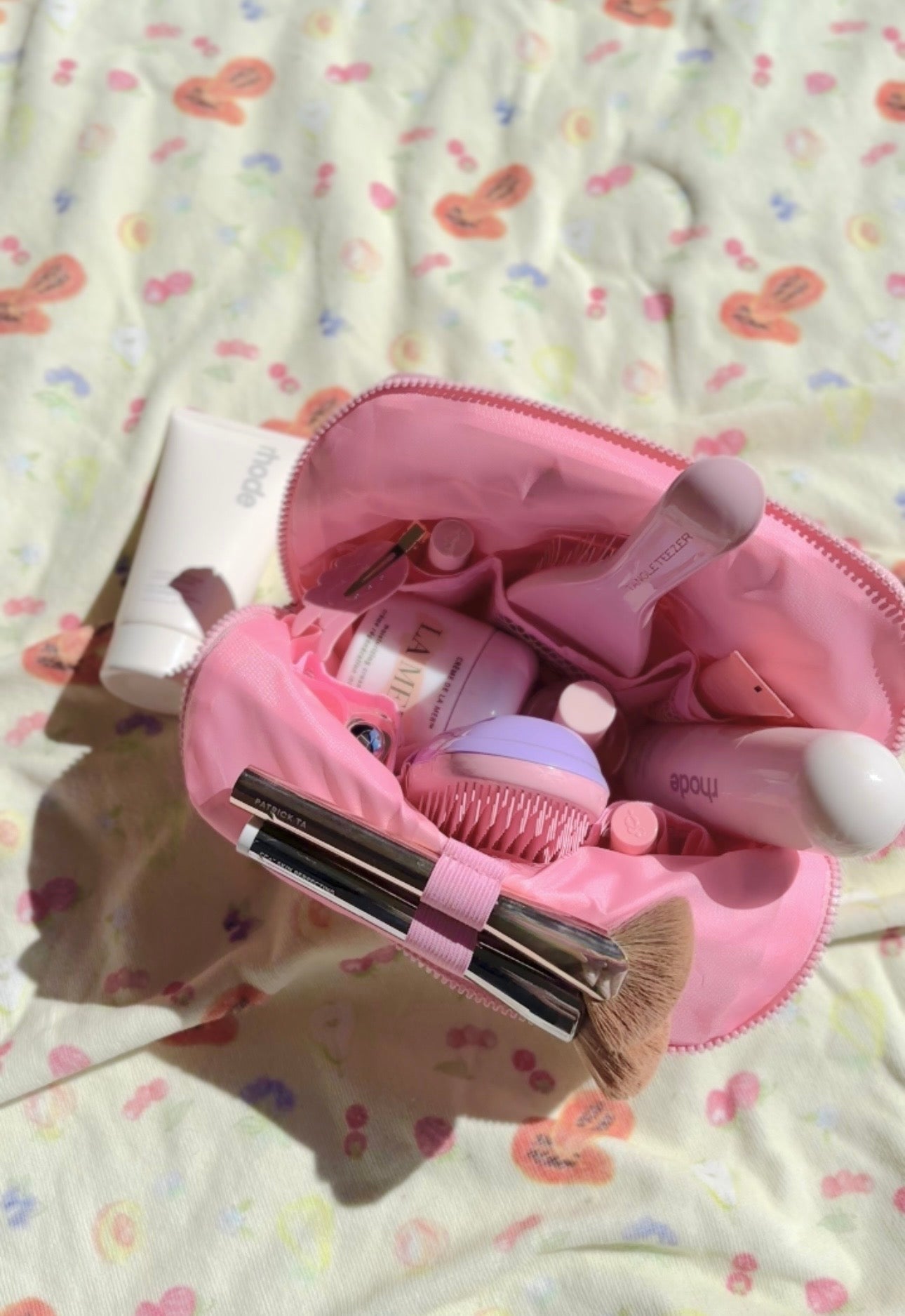 Open pink compact flex case with zippered inner pockets and multiple items