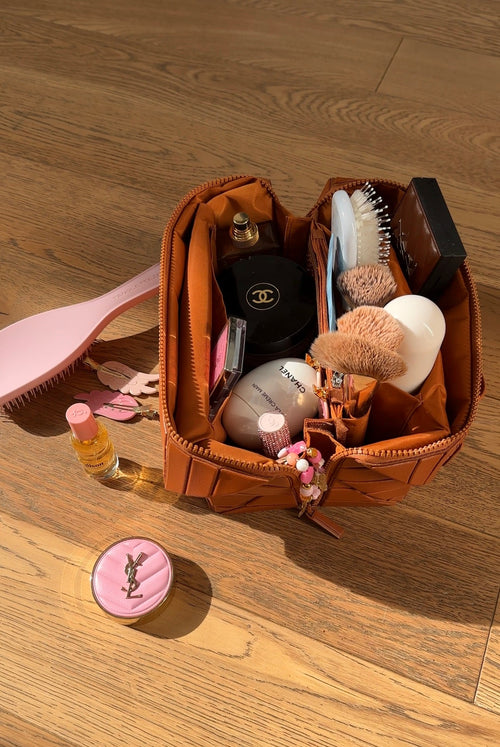Mocha-brown XL makeup case with open top and multiple compartments holding tools and bottles