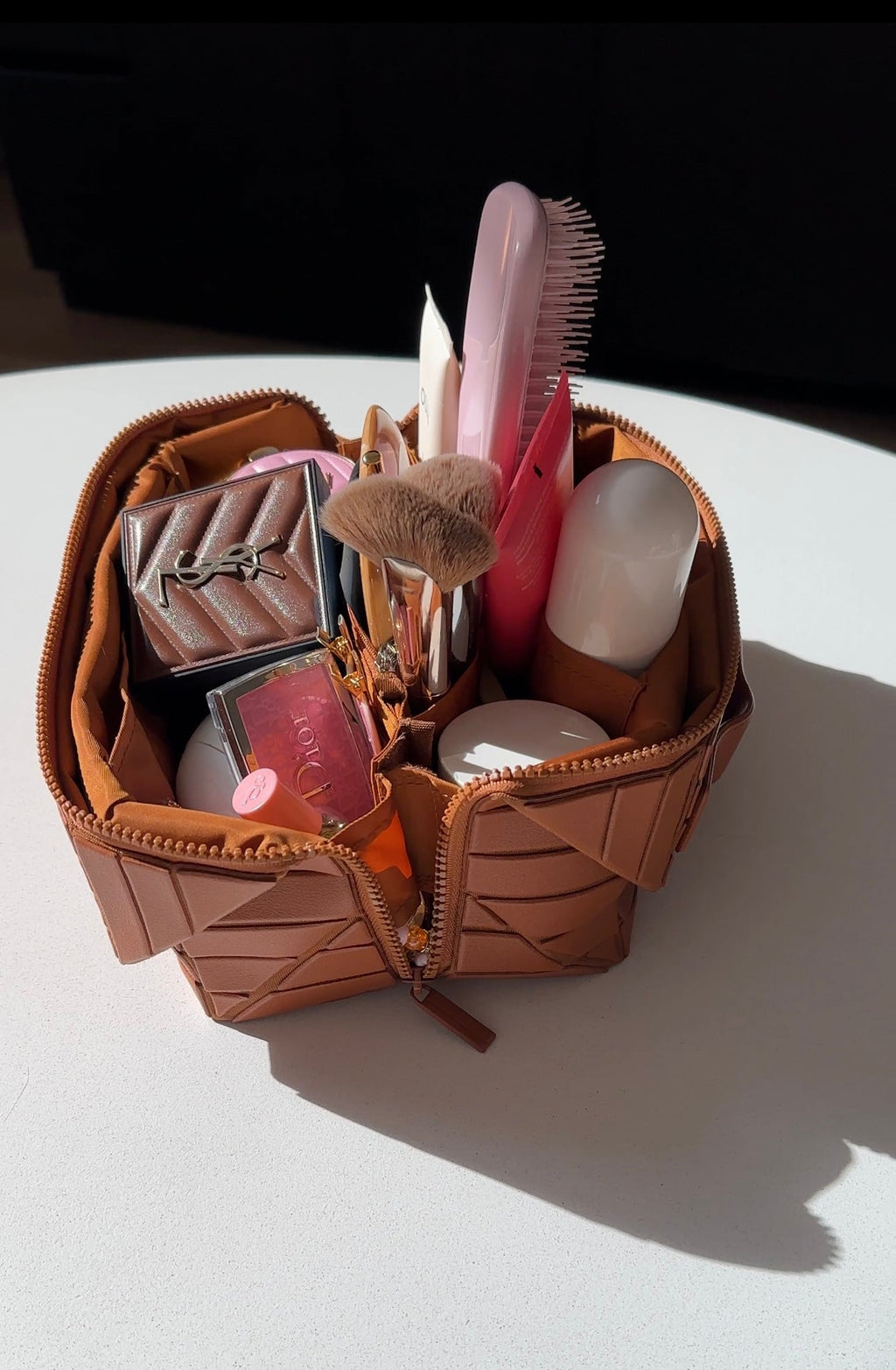 Mocha-brown XL cosmetic case open with brushes, compacts, and small beauty products inside