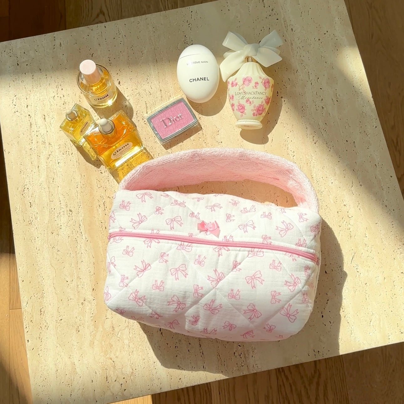 Light pink floral handbag with arched handle and central zipper; rounded pouch shape