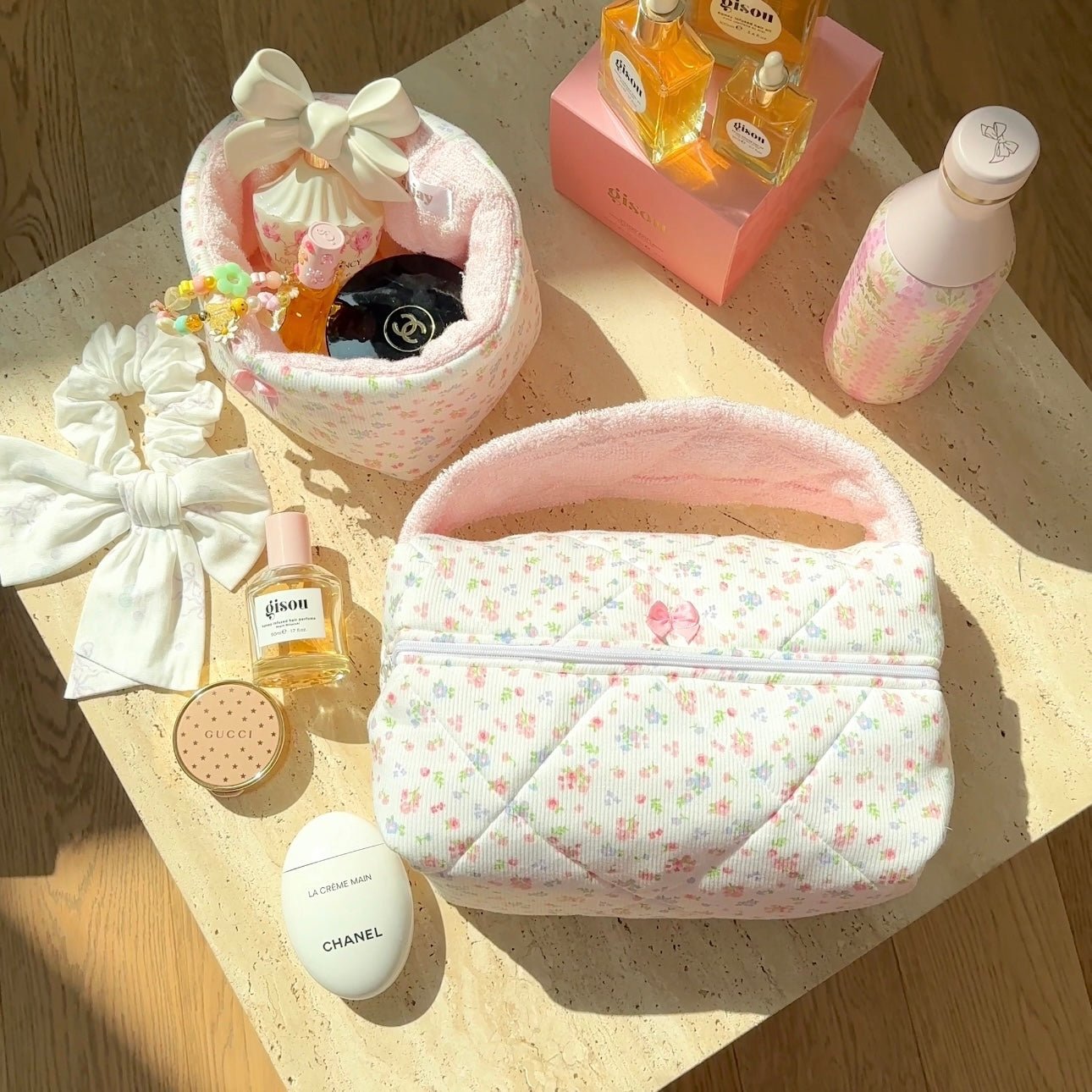 Pink floral fabric pouch-style handbag with bow handle and zip-top closure