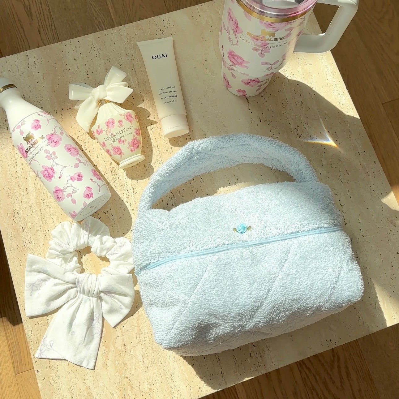 Light blue plush handbag with arched handle and zip top; small blue flower clasp
