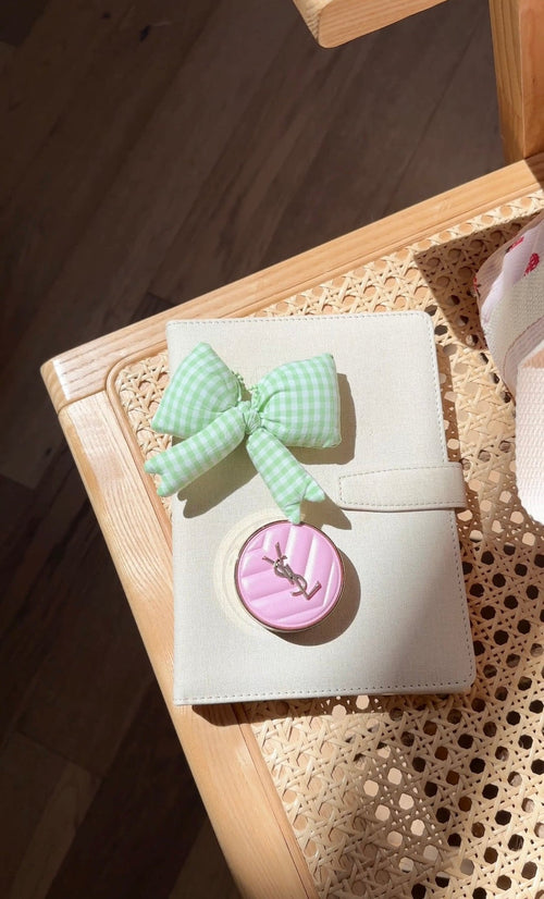 Green gingham oversized bow bag charm on white square with round pink button