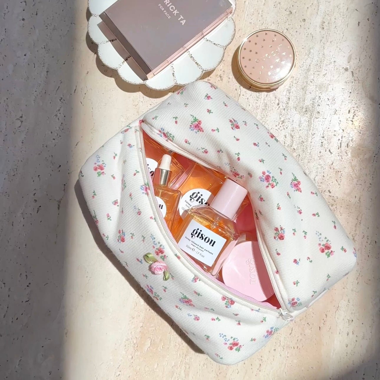 Beige floral zip pouch with scalloped trim, open top showing items inside
