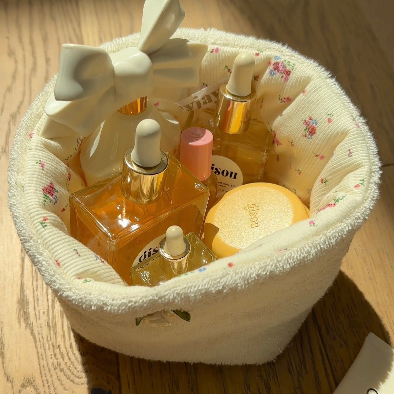 Cream fabric organizer basket, floral lining, open top with small bottles inside