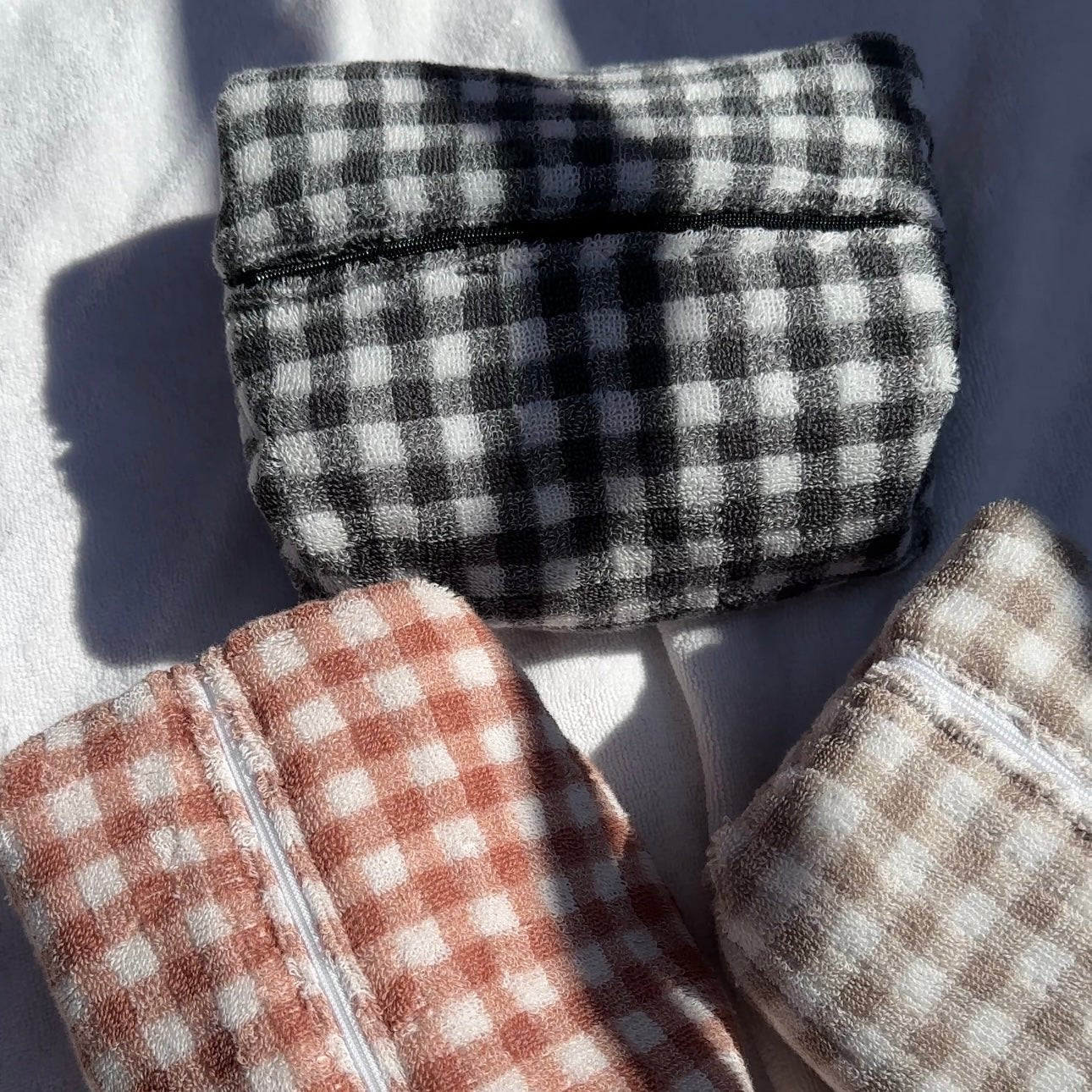 Assorted gingham fabric pieces: black gingham top with orange and light gingham folded sections.
