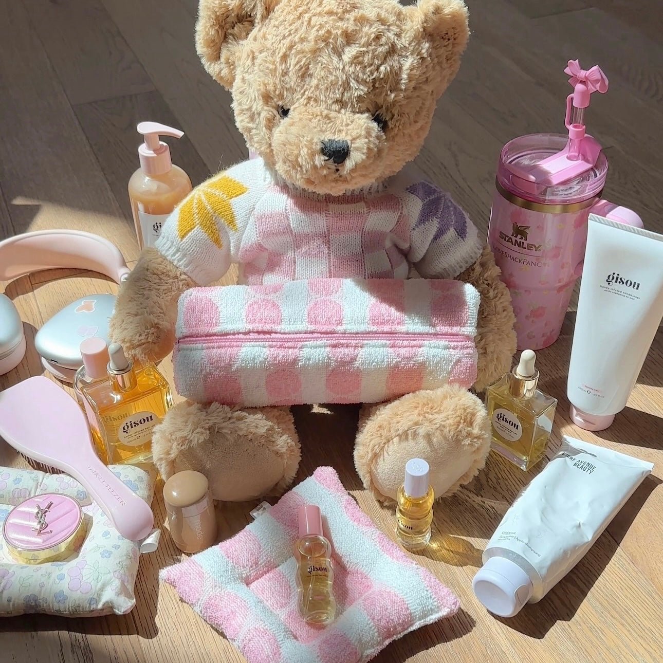 Small plush teddy bear in pink-and-white check outfit with soft folded towel