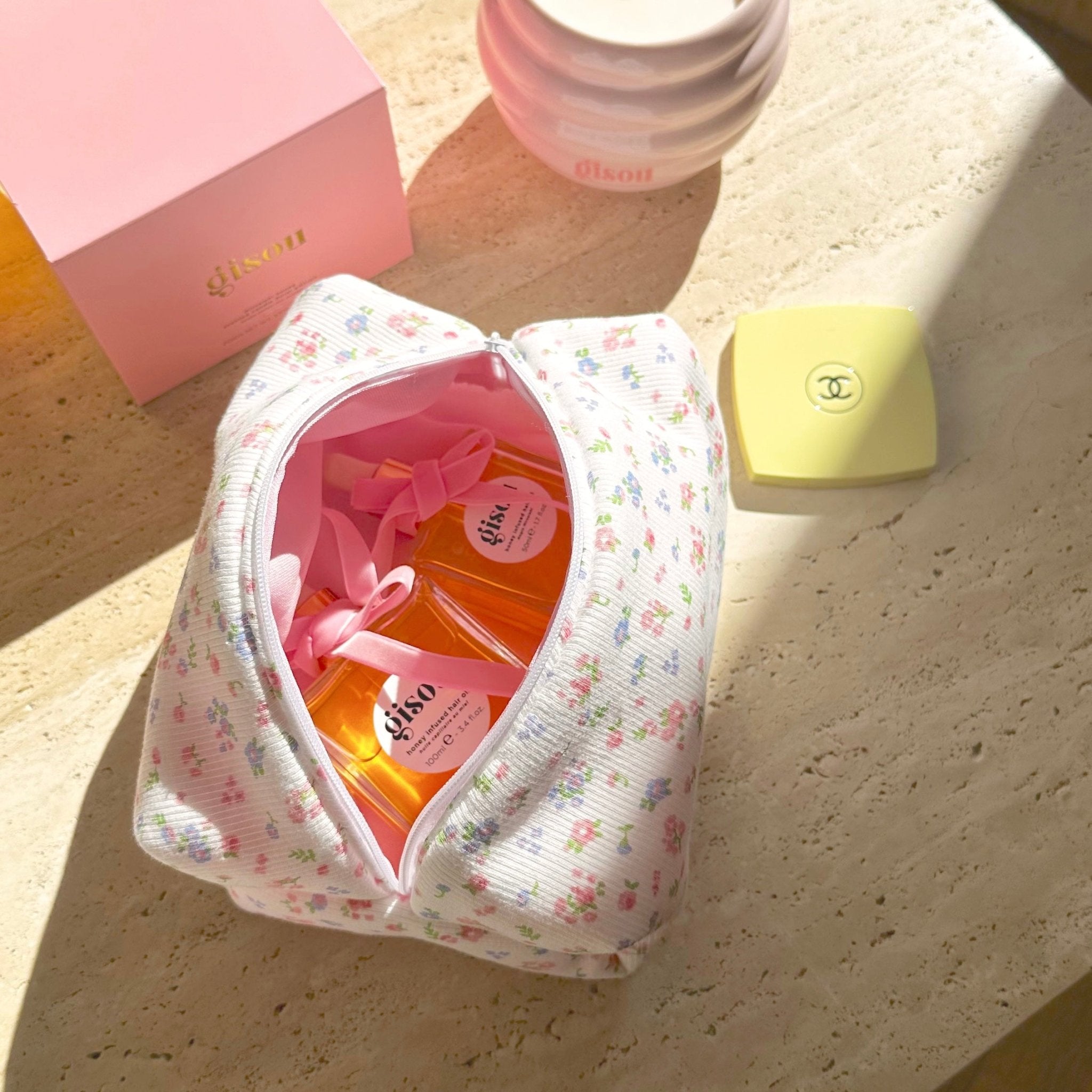 White floral zip pouch opened, pink inner lining and packaged items inside