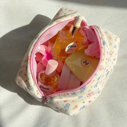 Cream floral fabric pouch with pink zipper, open with beauty bottles inside