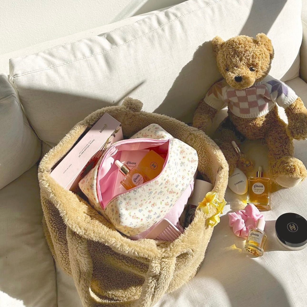 Floral zip pouch inside a teddy bear storage basket, with small accessories around