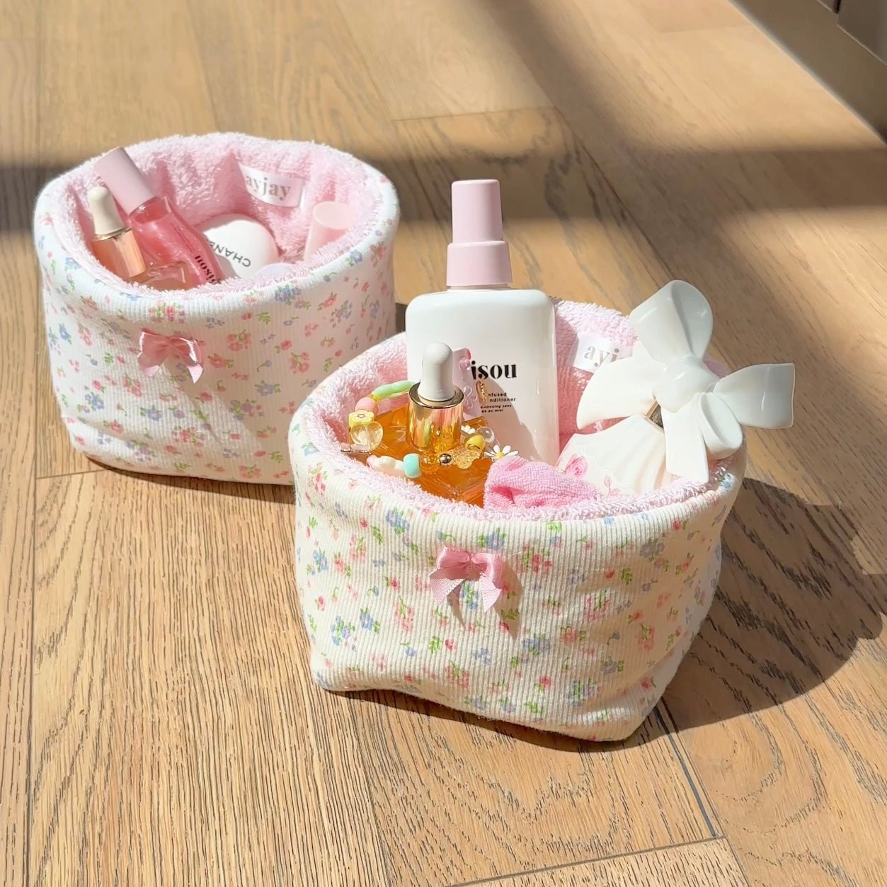 Floral fabric organizer basket with pink bow, holding cosmetics bottles