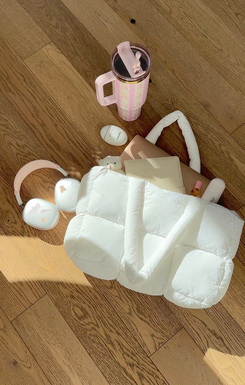 White quilted puffer duffle bag with loop handles, laid open