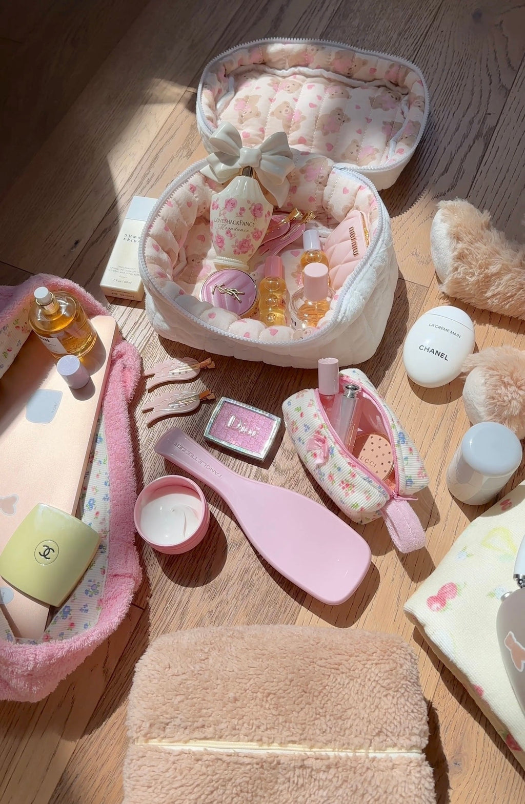 Overhead view of open white plush vanity bag with pink heart lining and assorted bottles.