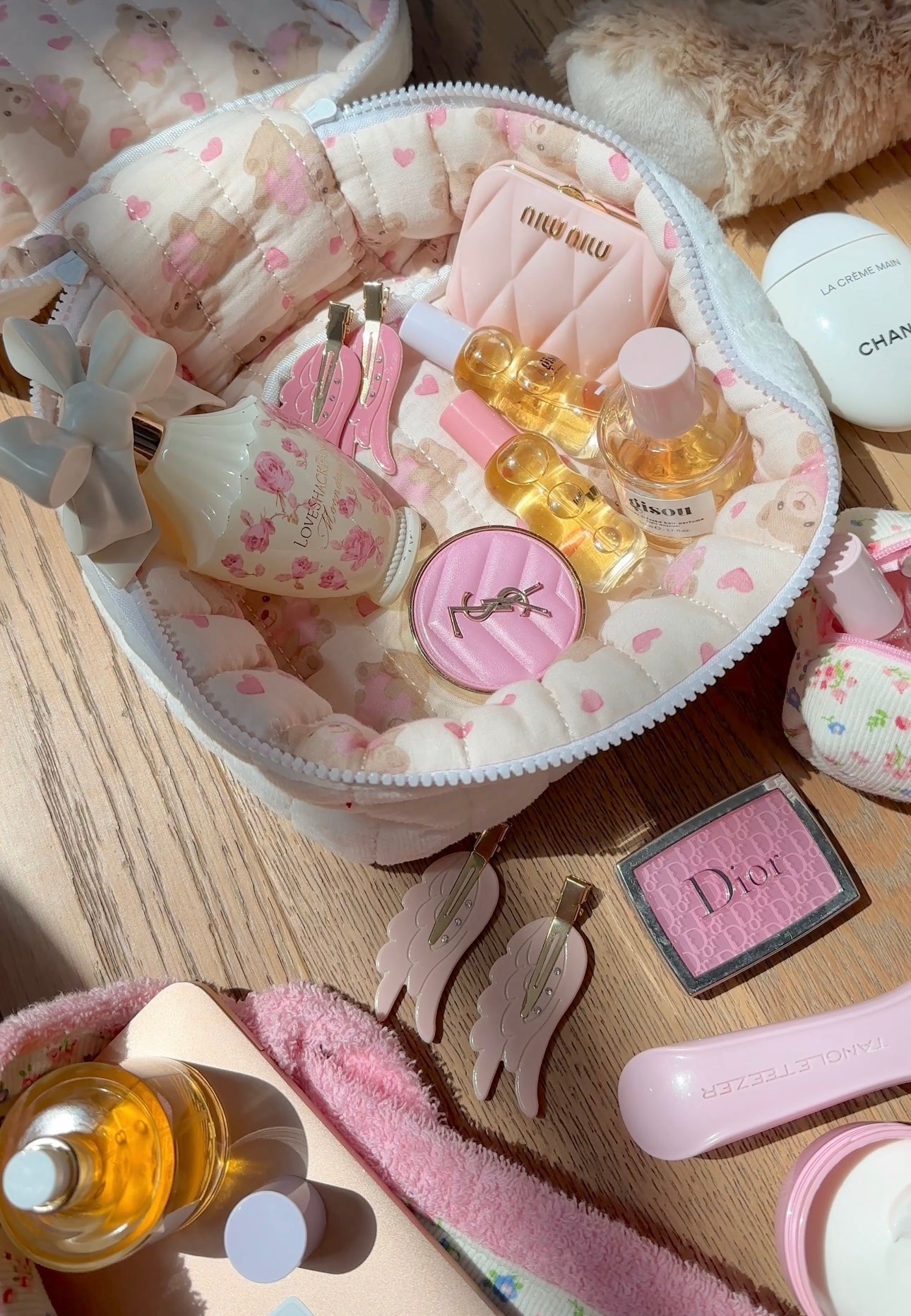 Open white plush vanity bag with pink heart print lining and pastel beauty bottles inside.