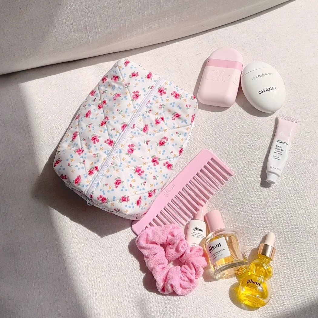 White floral zippered pouch with top handle, open view revealing pink items inside