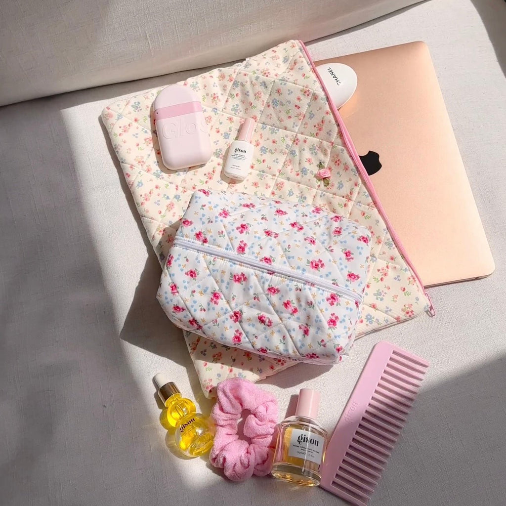 Padded white floral zip pouch with open top and front zipper, pink items inside