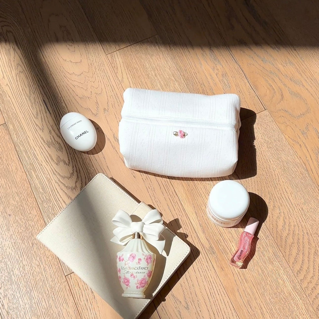 White knit jacquard pouch with lace-like pattern and small pink floral button clasp