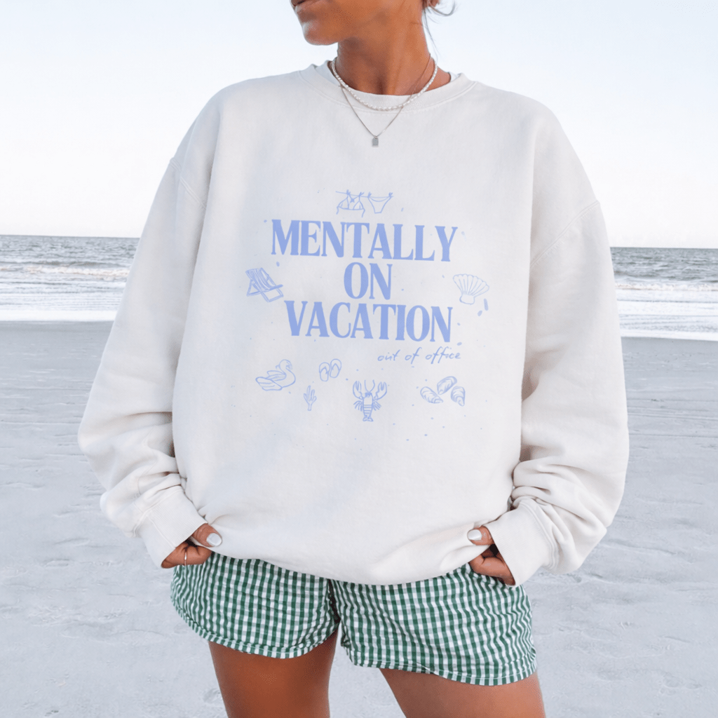 White crewneck sweatshirt with blue 'MENTALLY ON VACATION' graphic, long sleeves